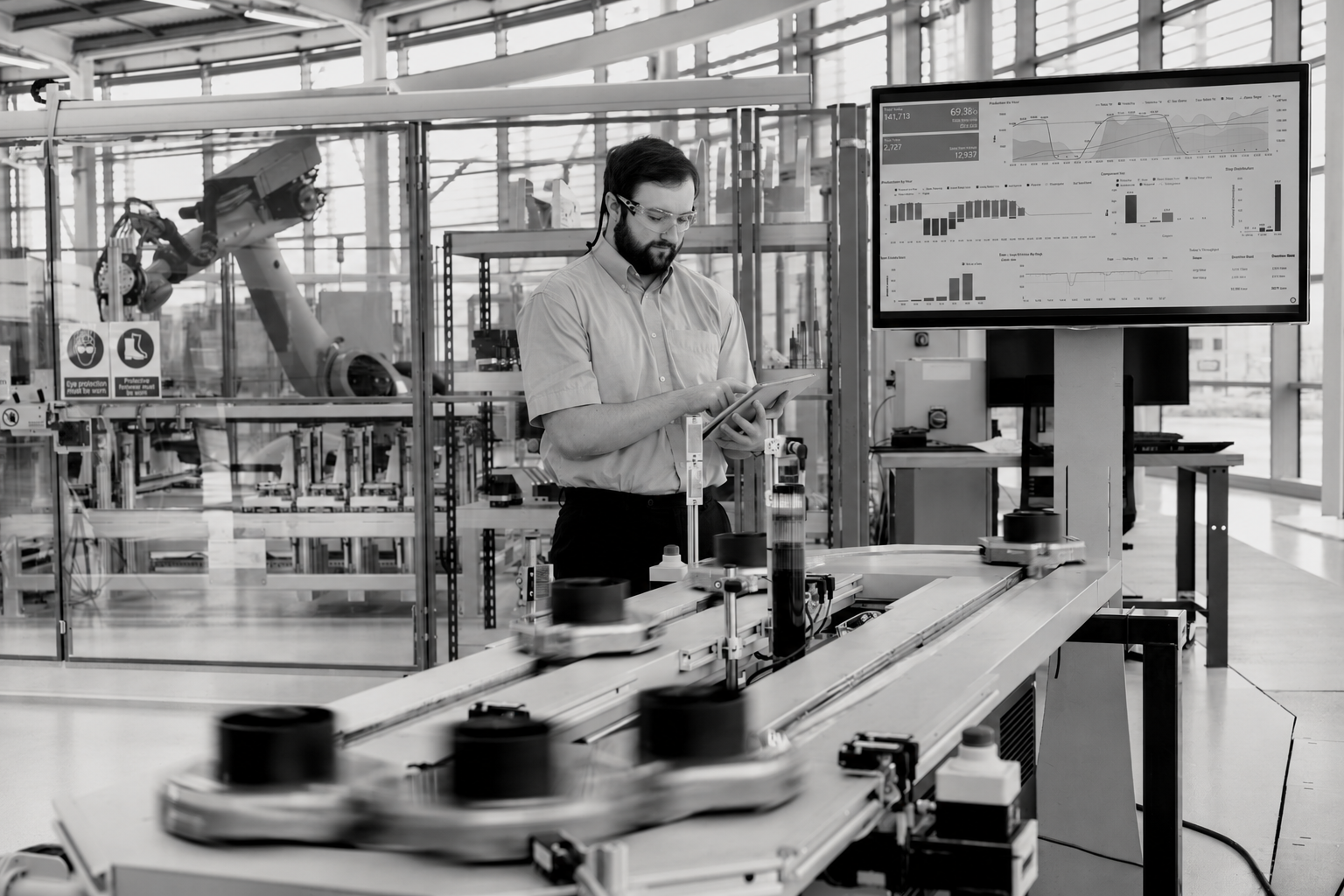 Factory operator beside automated machinery and an operational display